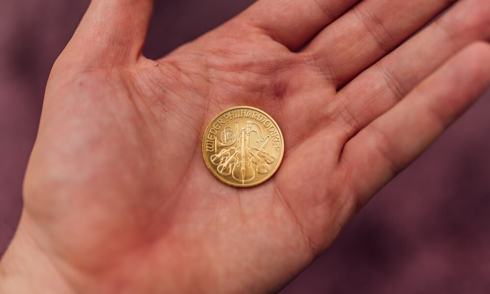 A gold coin resting in the palm of an open hand